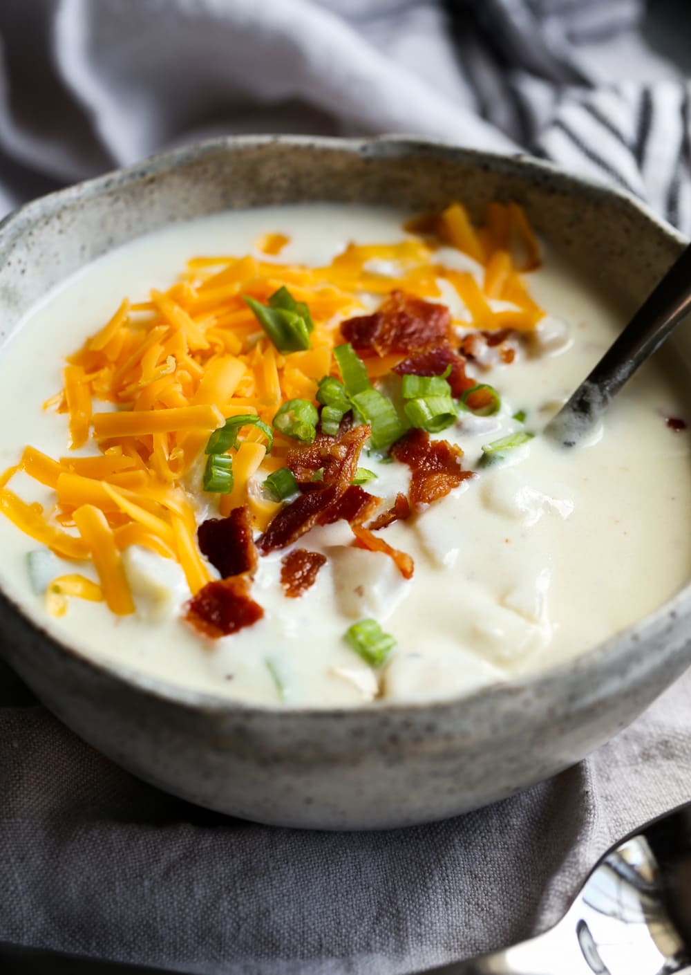 Bowl of baked potato soup with cheese.