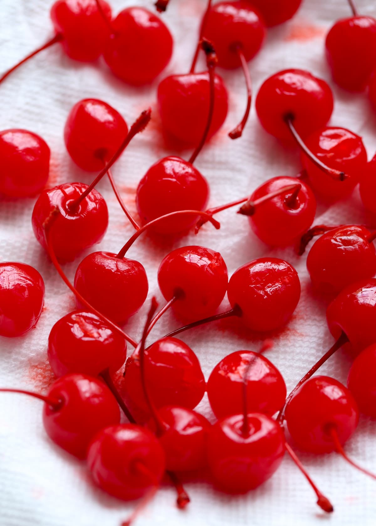 Scattered Maraschino cherries on a piece of parchment paper.