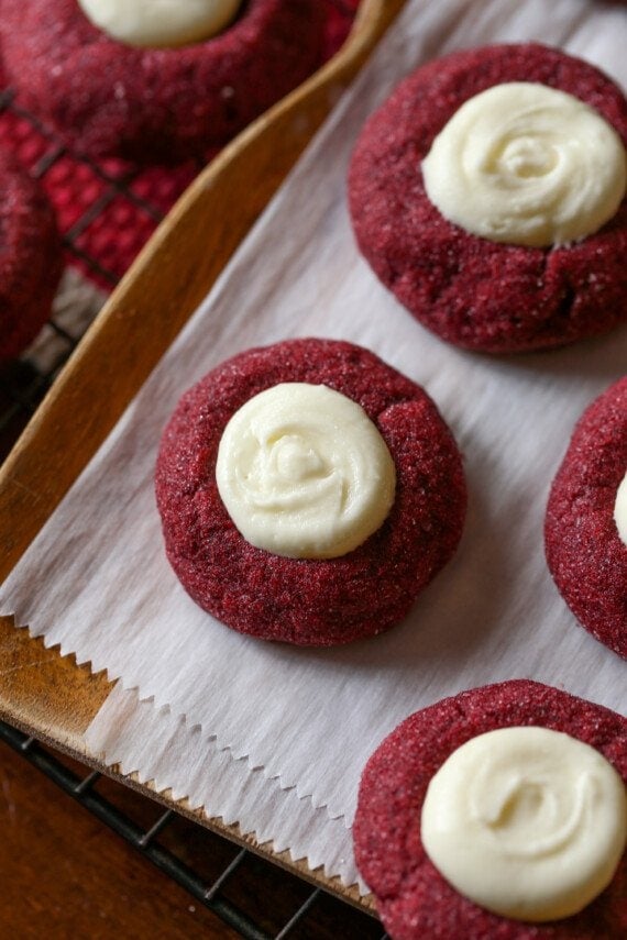 Red cookies topped with icing on a piece of parchment paper