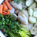 uncooked Chicken potatoes carrots and herbs in a pot