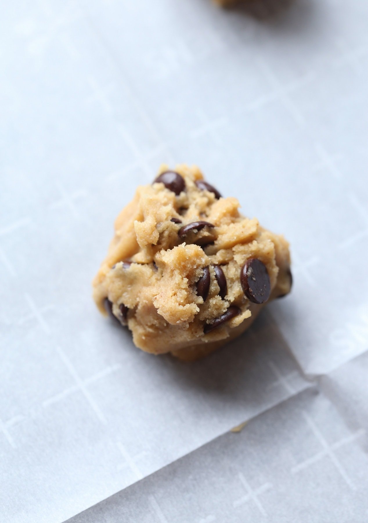 A ball of cookie dough on a parchment lined baking sheet