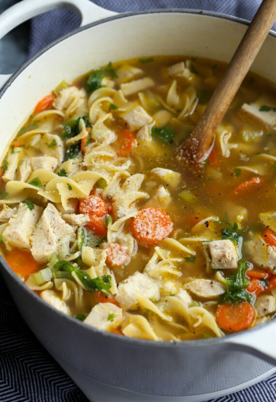homemade chicken soup in a pot with parmesan cheese sprinkled on top