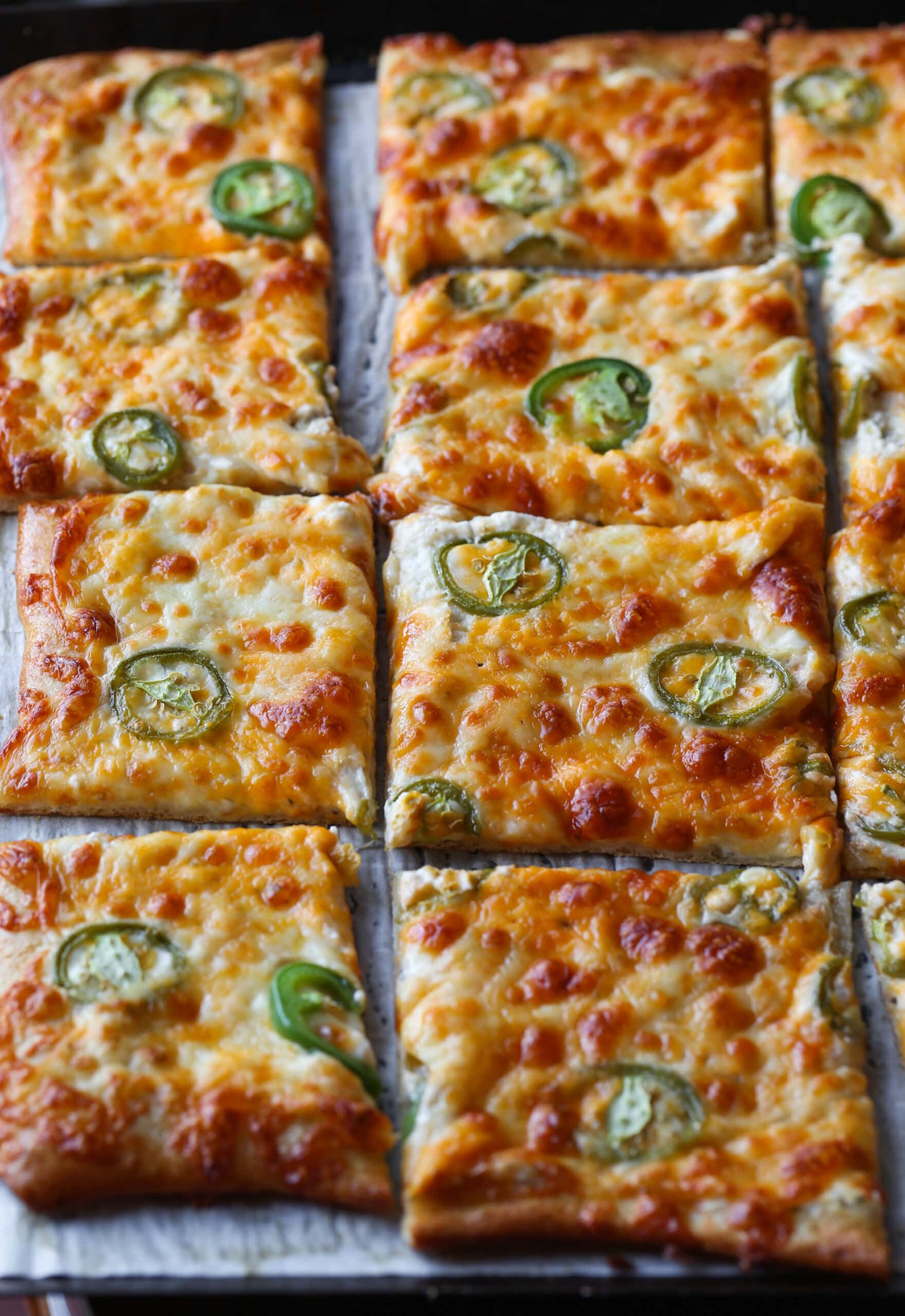 jalapeno pizza on a baking sheet sliced