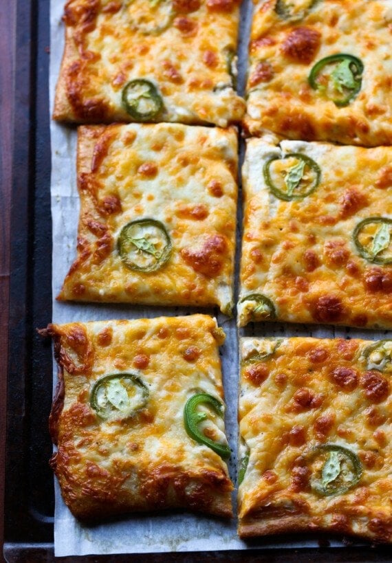 Pizza topped with jalapenos and cheese sliced on a tray