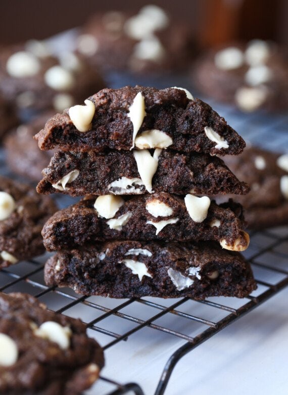 Chocolate Cookies with melted white chocolate chips stacked on a cooling rack