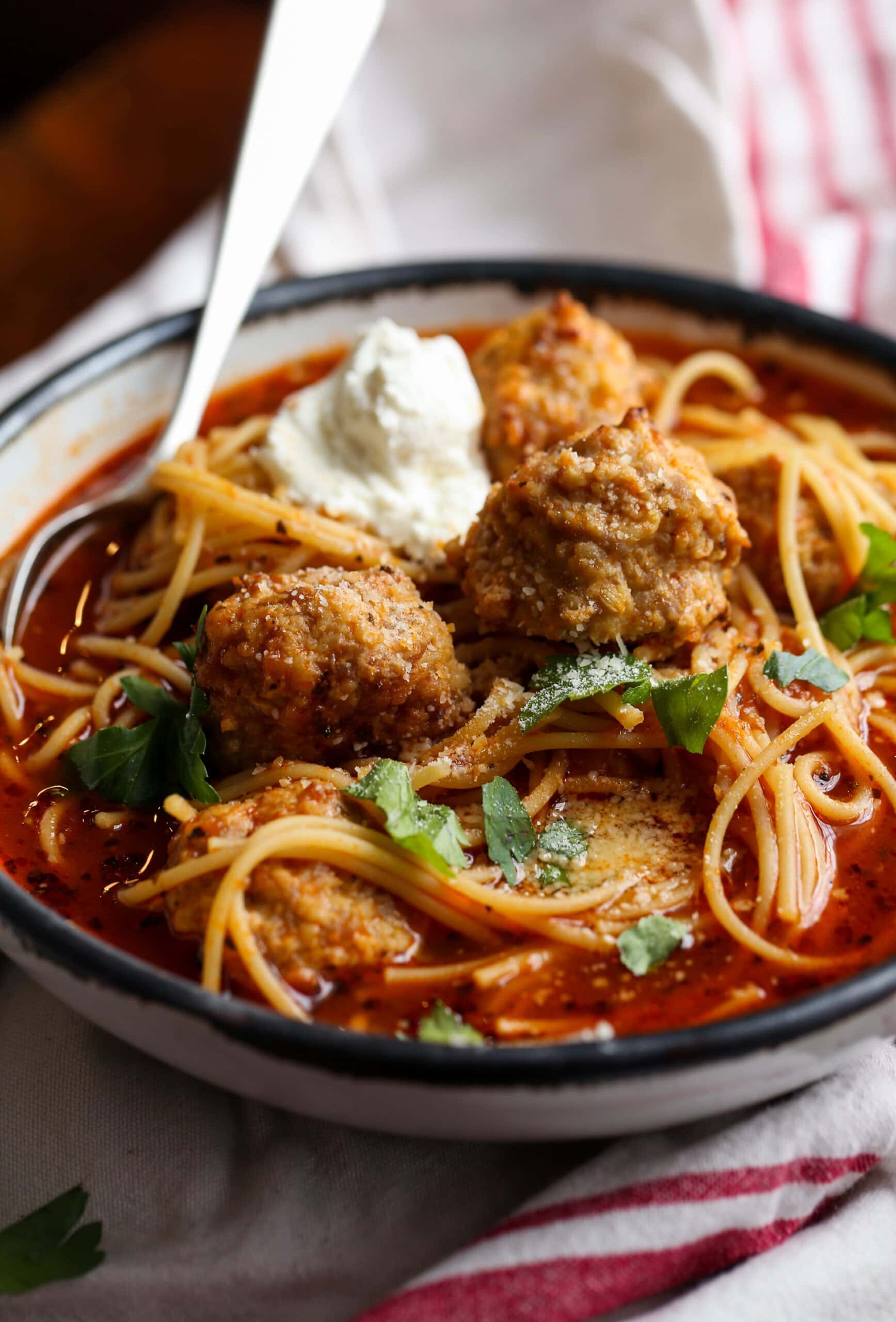 Spaghetti and Meatball soup in a bowl with ricotta cheese and parsley