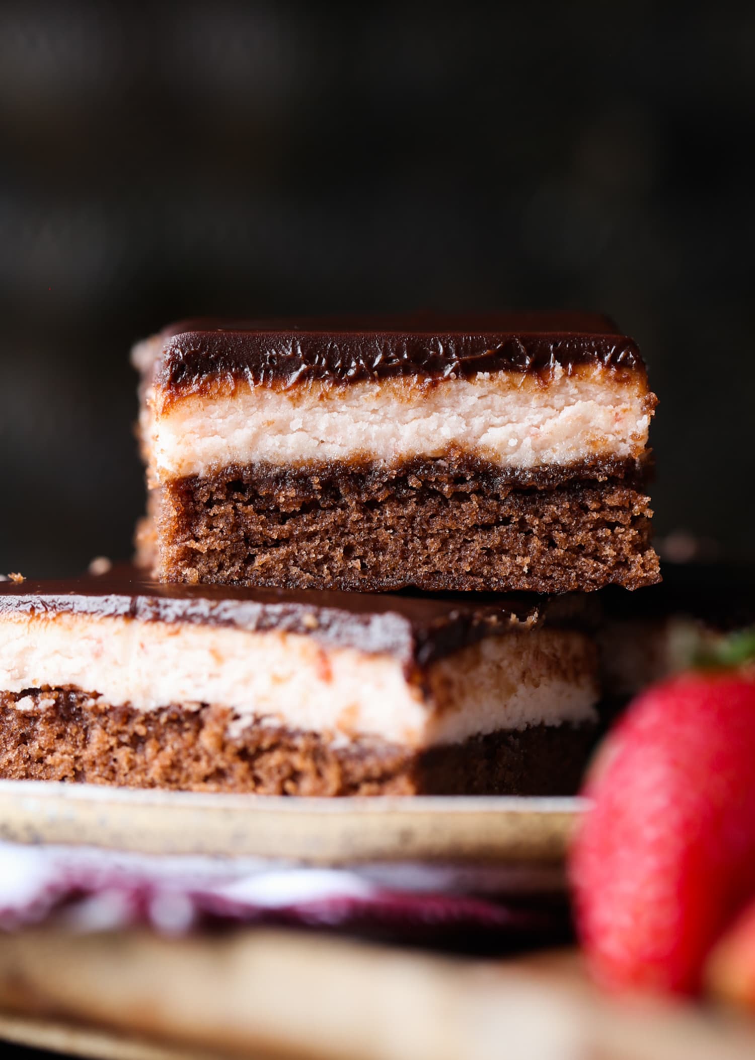 Three layered fudge brownie topped with strawberry frosting and chocolate ganache