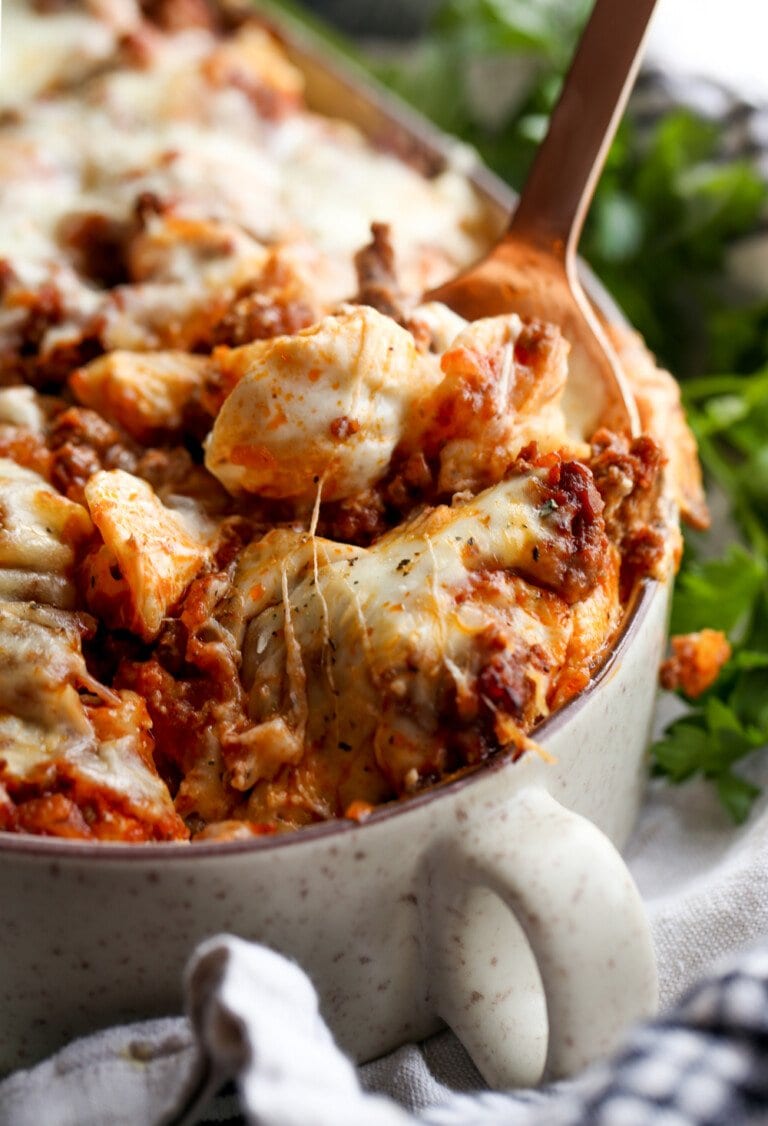 Unstuffed shell pasta casserole with spoon and melting cheese