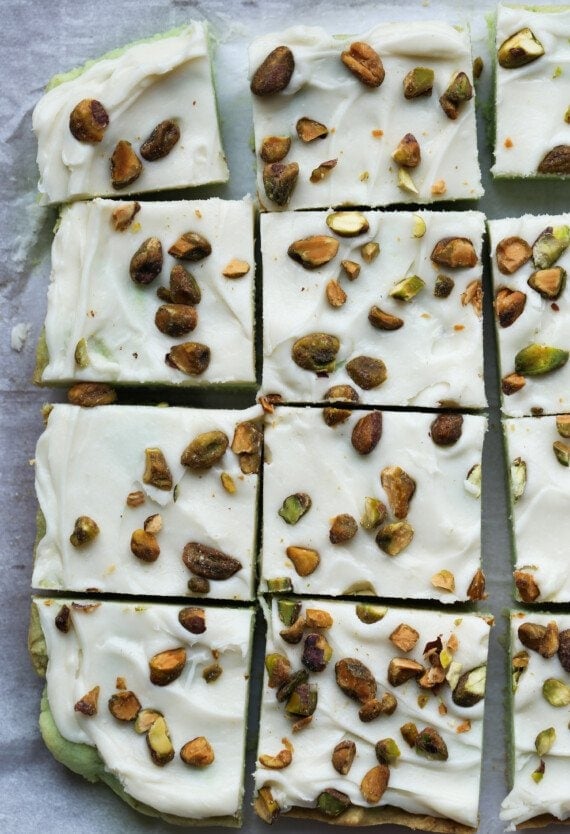 Pistachio Bars topped with cream cheese frosting and chopped pistachios cut on a serving plate from above.