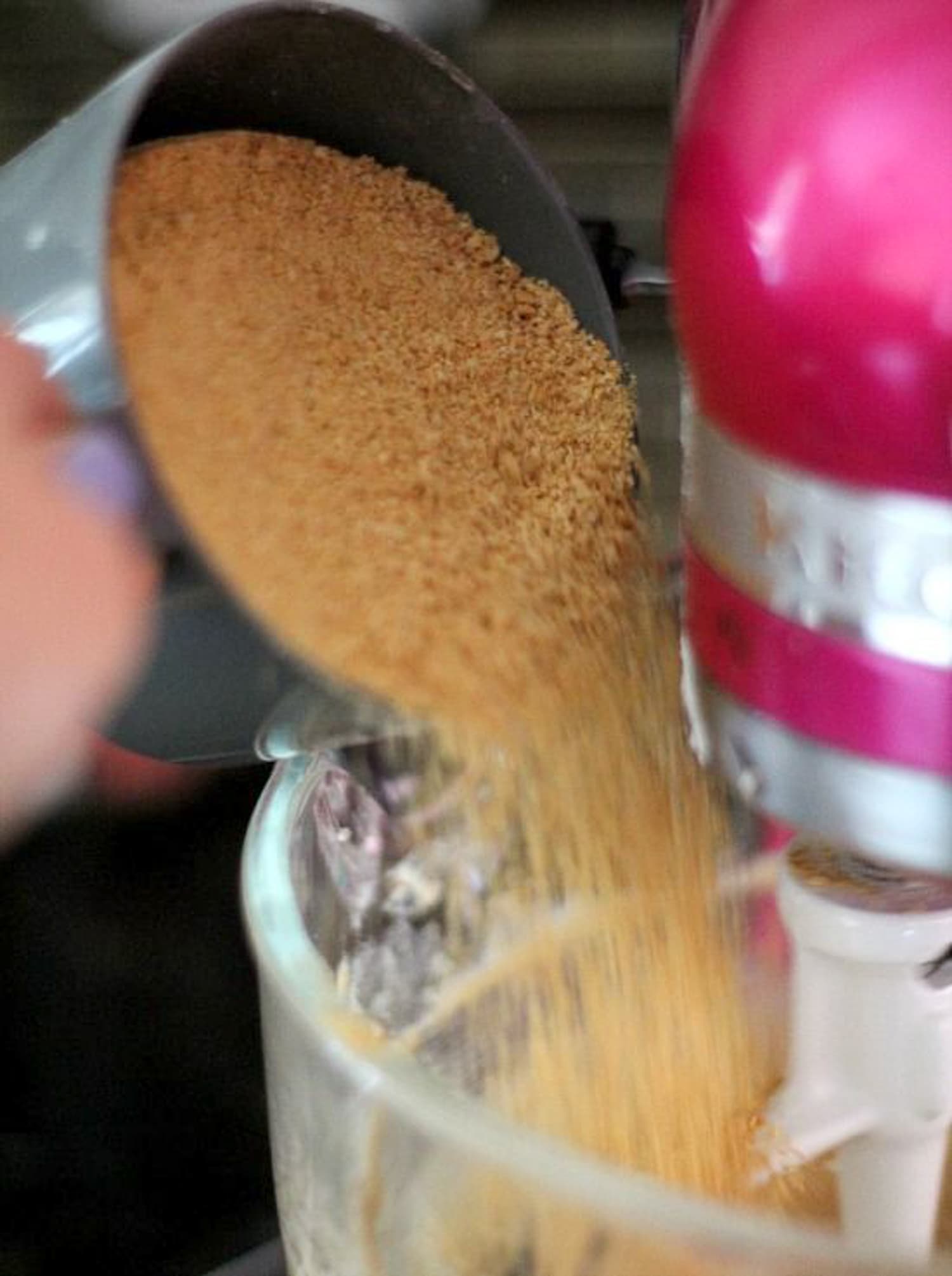 pouring graham cracker crumbs into the mixing bowl of a stand mixer