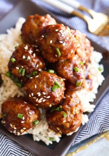 Sesame meatballs on a plate of rice.