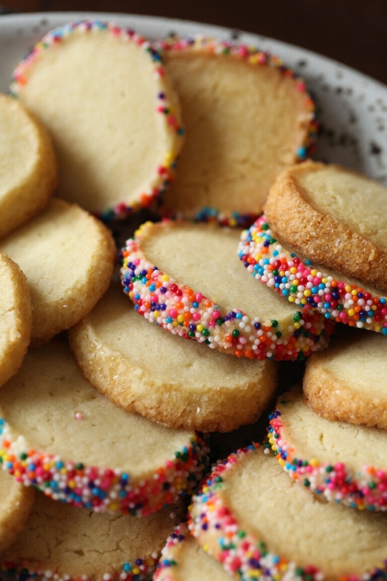 Plate of butter cookies with their edges coated with sprinkles.