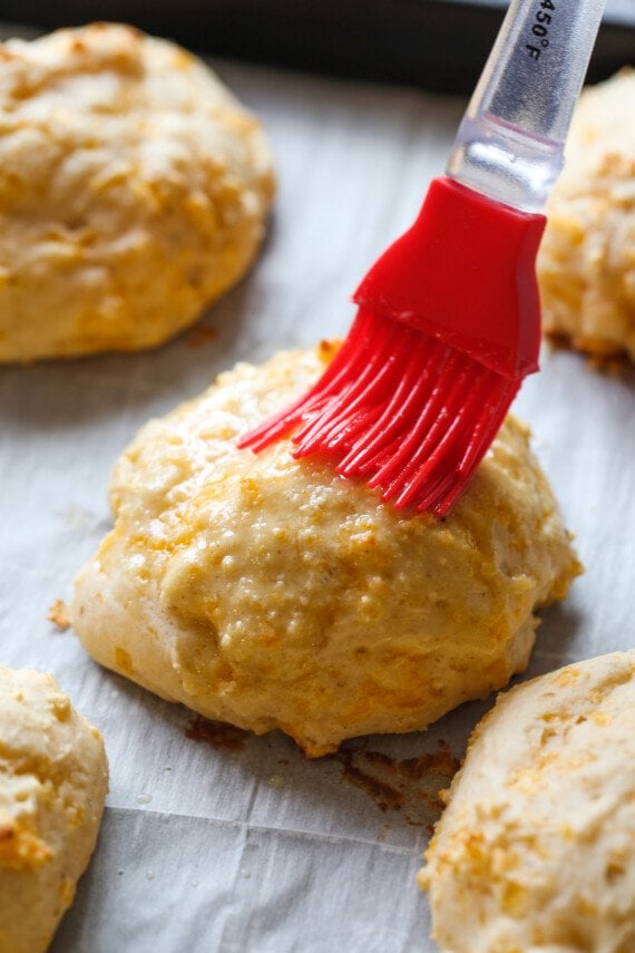 brushing melted butter on a baked biscuit