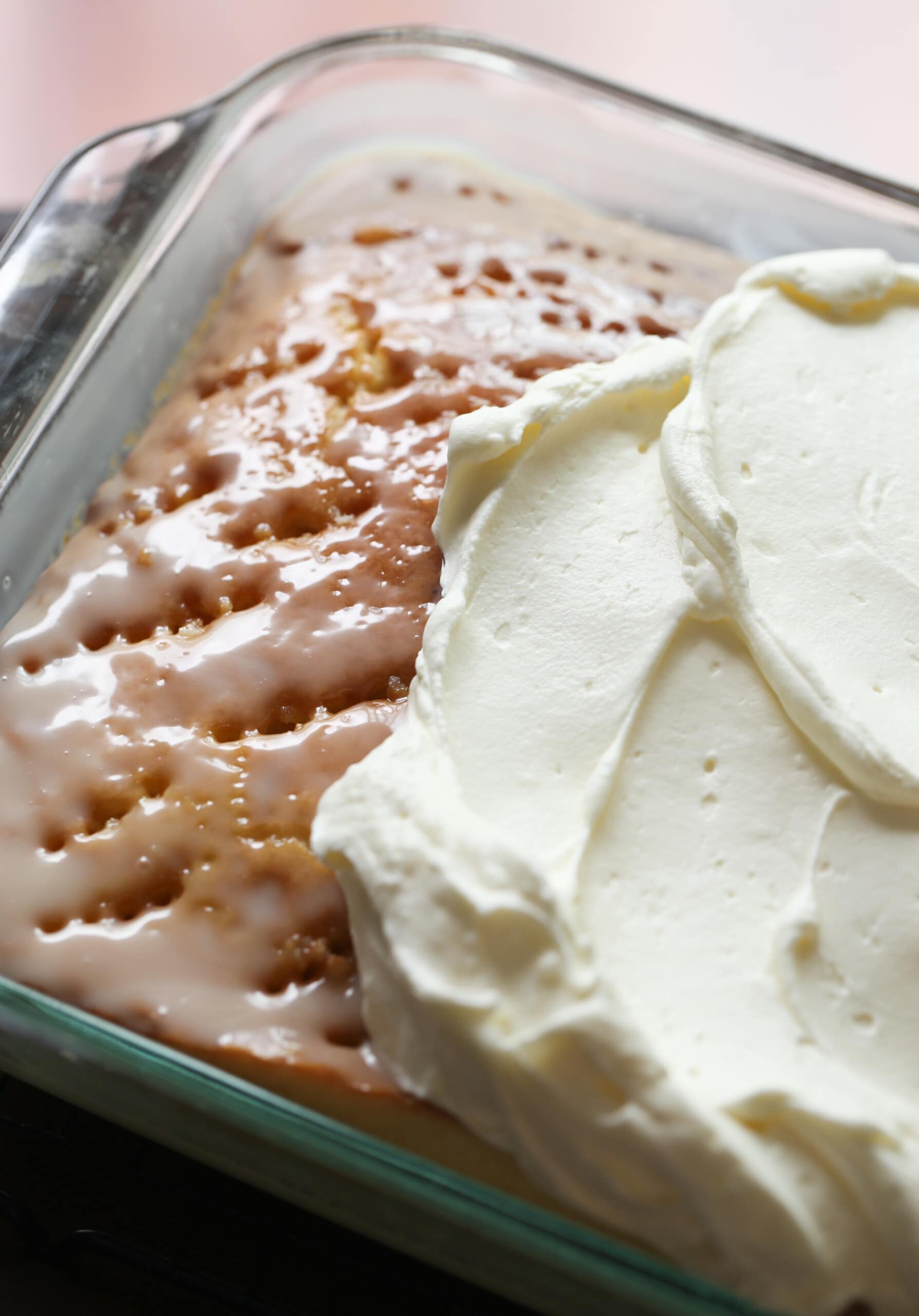 Poke cake being frosted with whipped topping