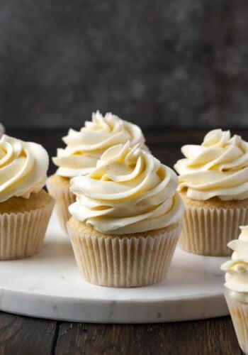 Cupcakes frosted with swirls of Swiss meringue buttercream frosting on a marble cake stand.