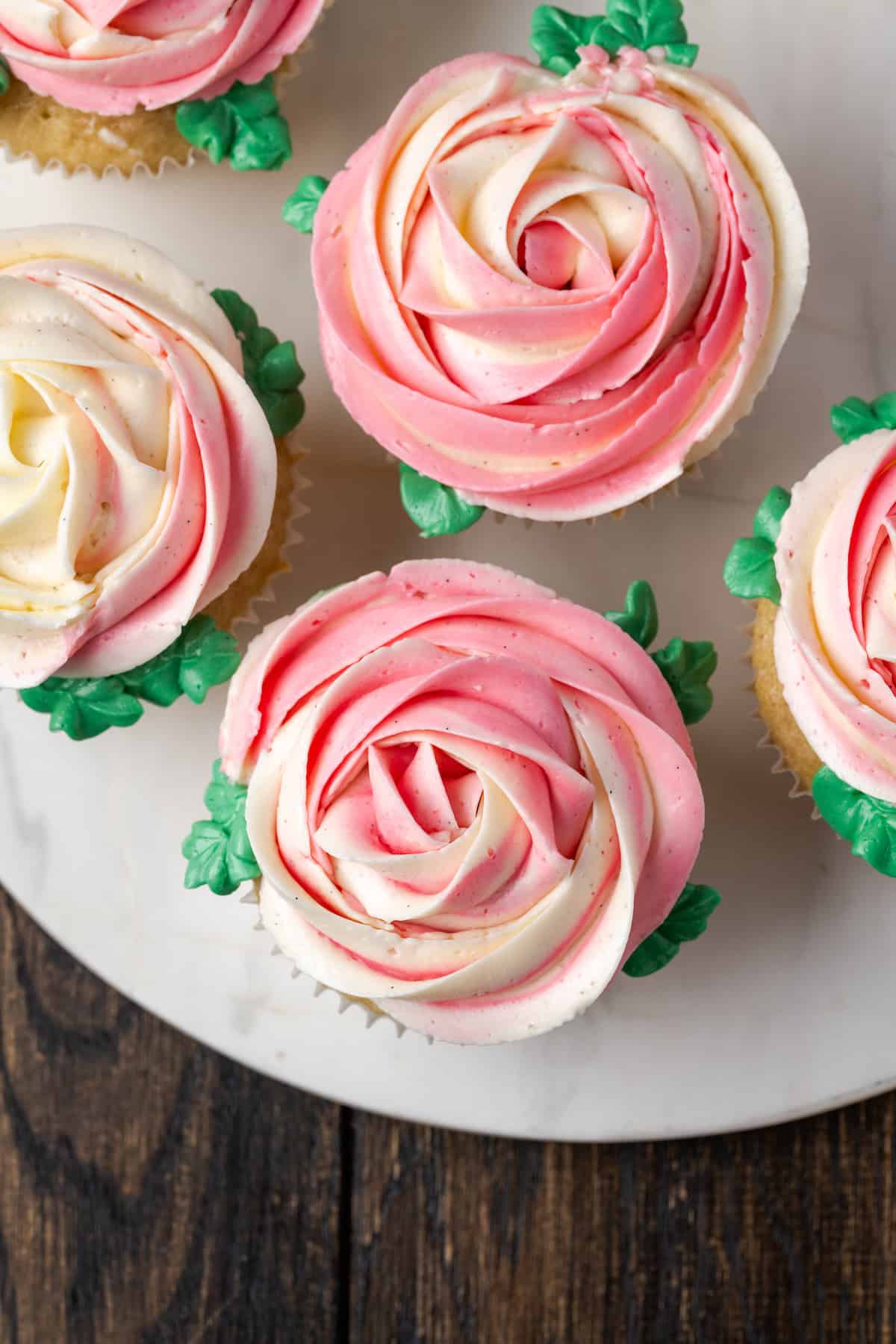 Overhead view of cupcakes frosted with pink and white ombre Swiss meringue buttercream roses.