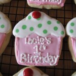 A Cookie Decorated to Look like a Cupcake with "Lacie's 1st Birthday" Written in Icing