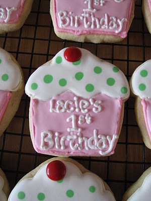 A Cookie Decorated to Look like a Cupcake with "Lacie's 1st Birthday" Written in Icing
