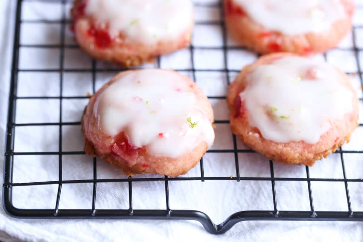 cherry cookies with lime icing on a wire cooling rack