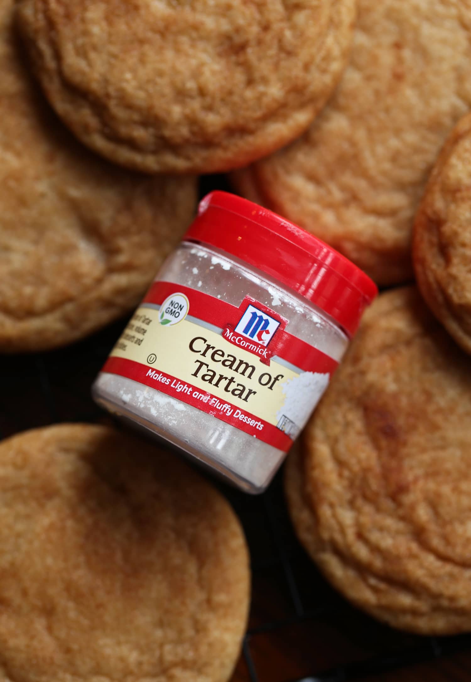 A container of cream of tartar on a rack of snickerdoodle cookies