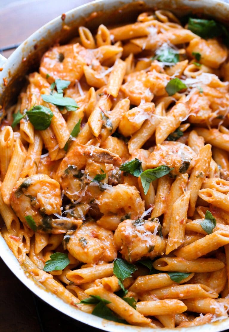 Creamy shrimp pasta in a large skillet garnished with fresh basil