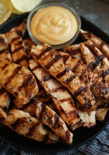 Grilled chicken tenders with a bowl of dip.