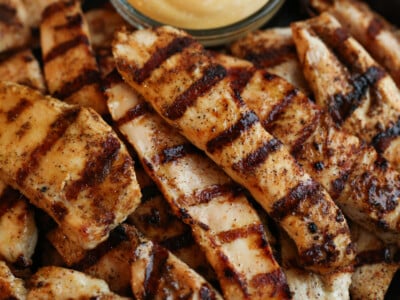 Grilled chicken tenders with a bowl of dip.