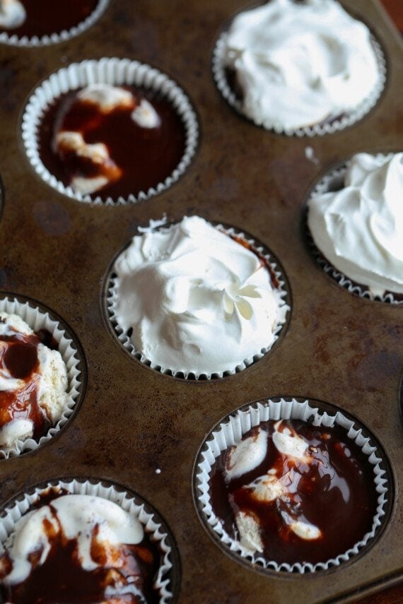 Topping ice cream with cool whip and hot fudge in a muffin tin