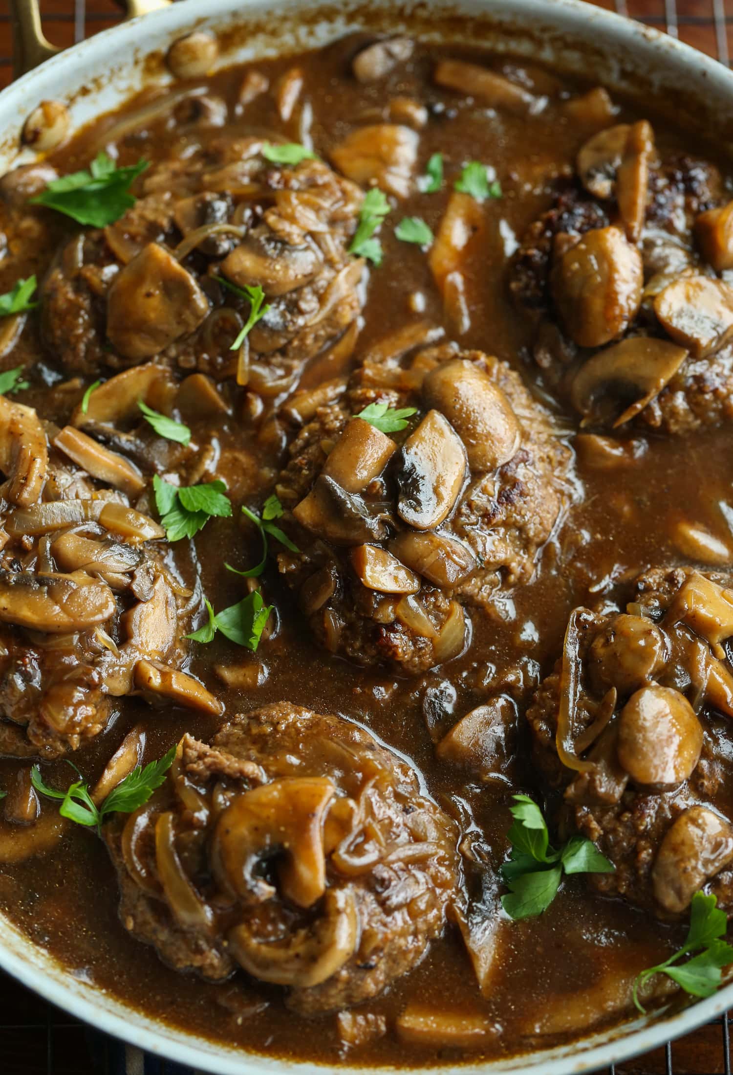 Salisbury Steak with gravy and garnished with parsley in a skillet