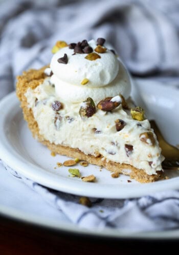 cannoli pie sliced on a plate topped with pistachios and chocolate chips