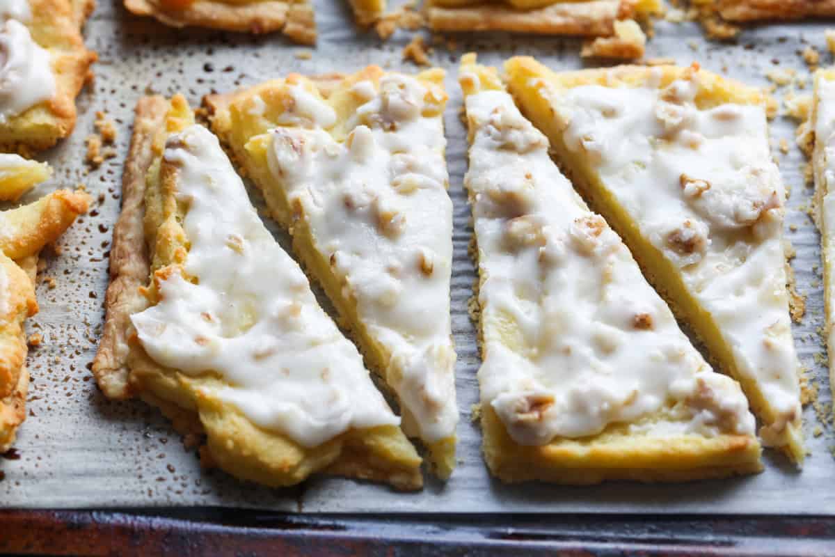 Slices of Danish Kringle topped with powdered sugar icing and nuts