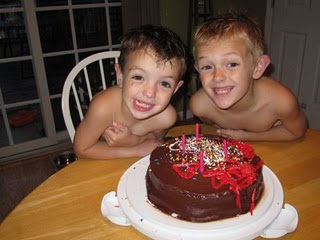 My boys sitting at the table in front of their cake with big smiles on their faces