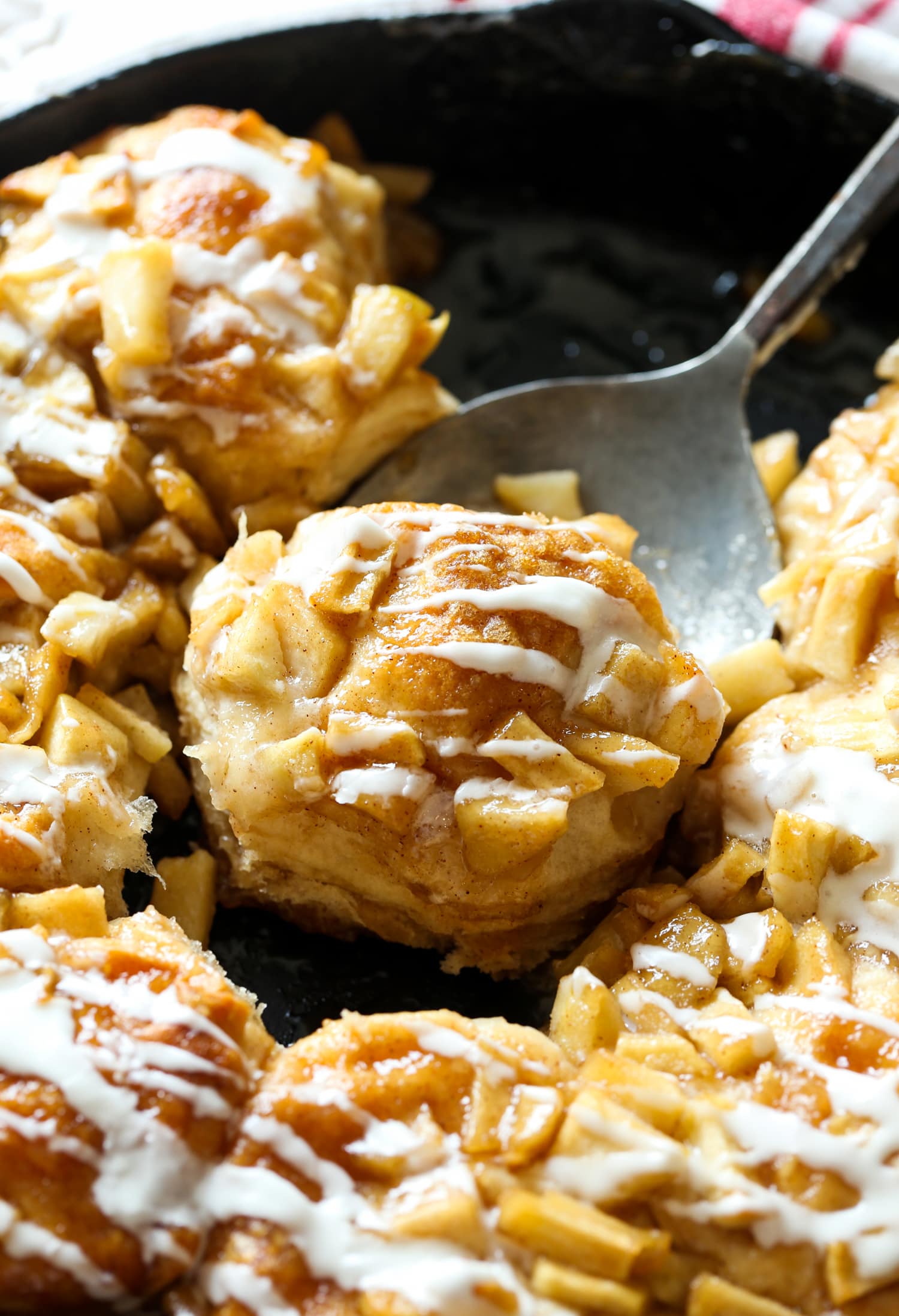 Serving an apple biscuit from a skillet with a spoon.