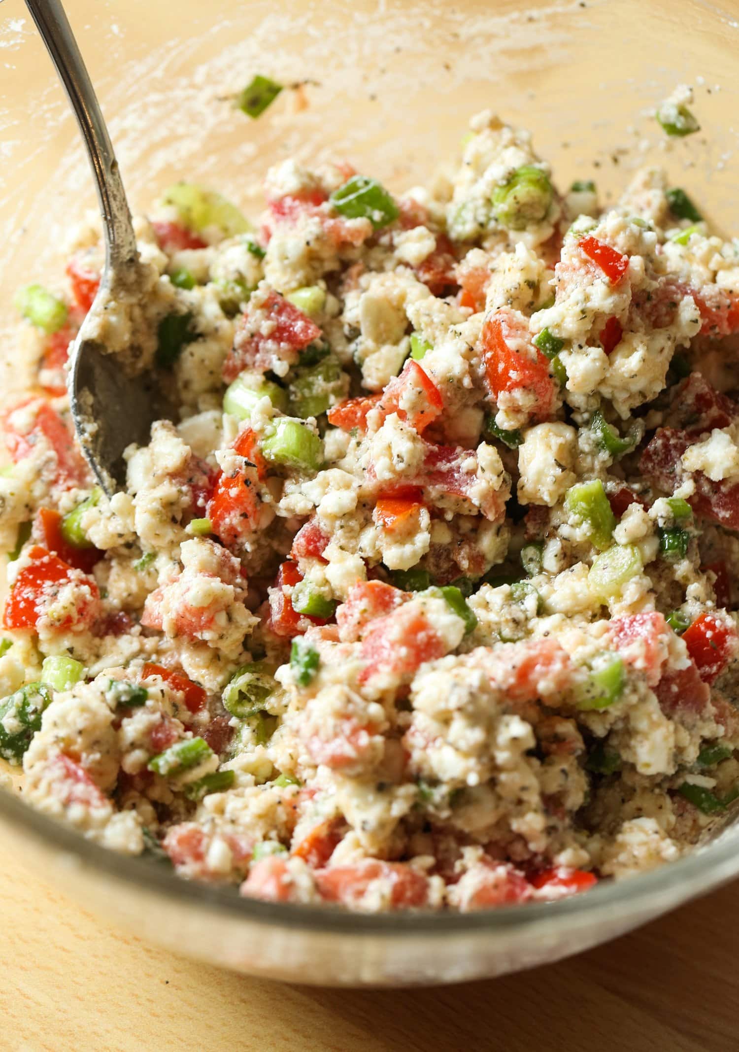 Feta cheese, green onions, tomatoes, and seasoning in a bowl