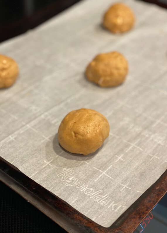 peanut butter cookie dough balls on a baking sheet lined with parchment paper
