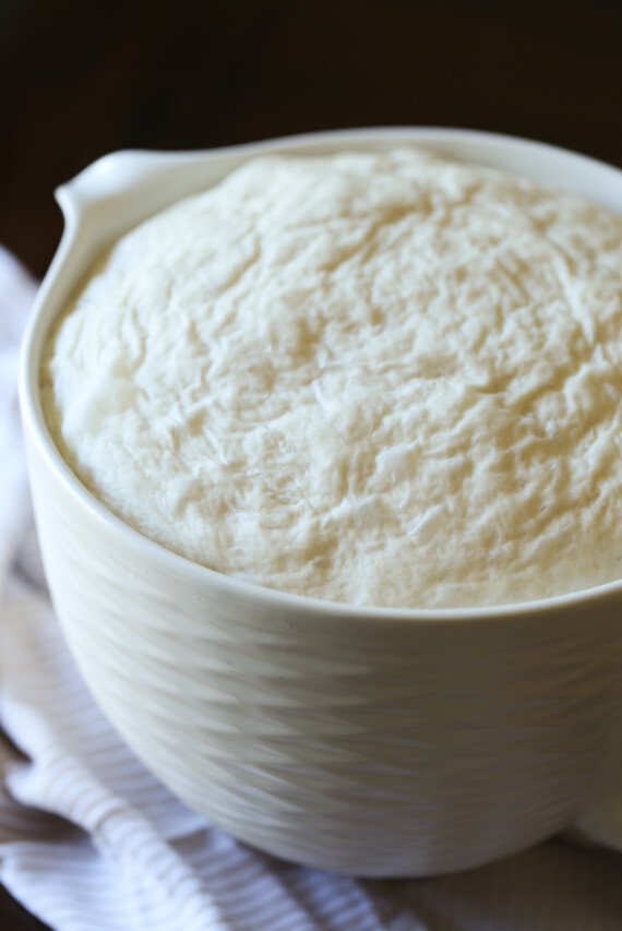 A mixing bowl full of risen bread dough.