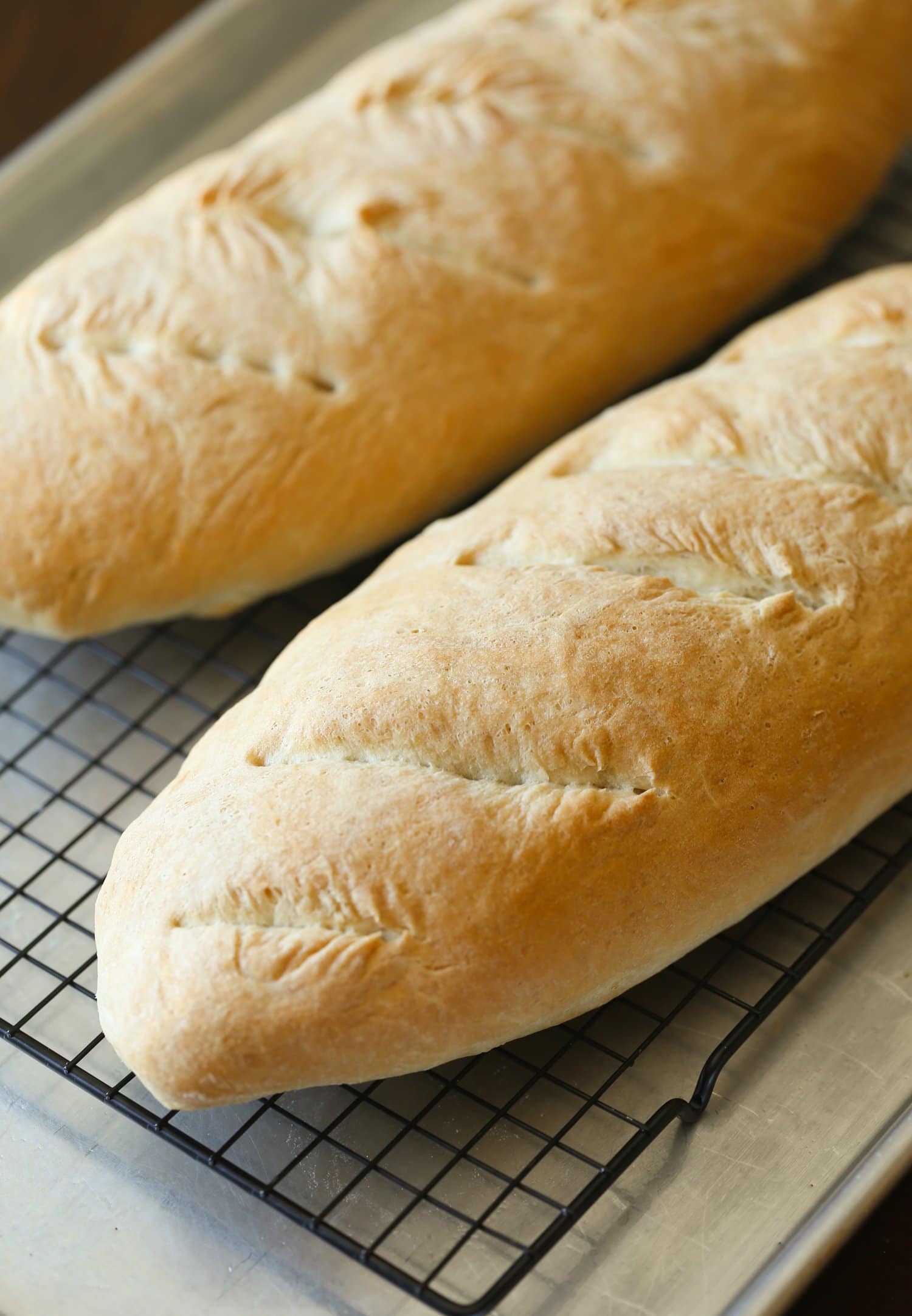 Two loaves of French bread on a cooling rack.