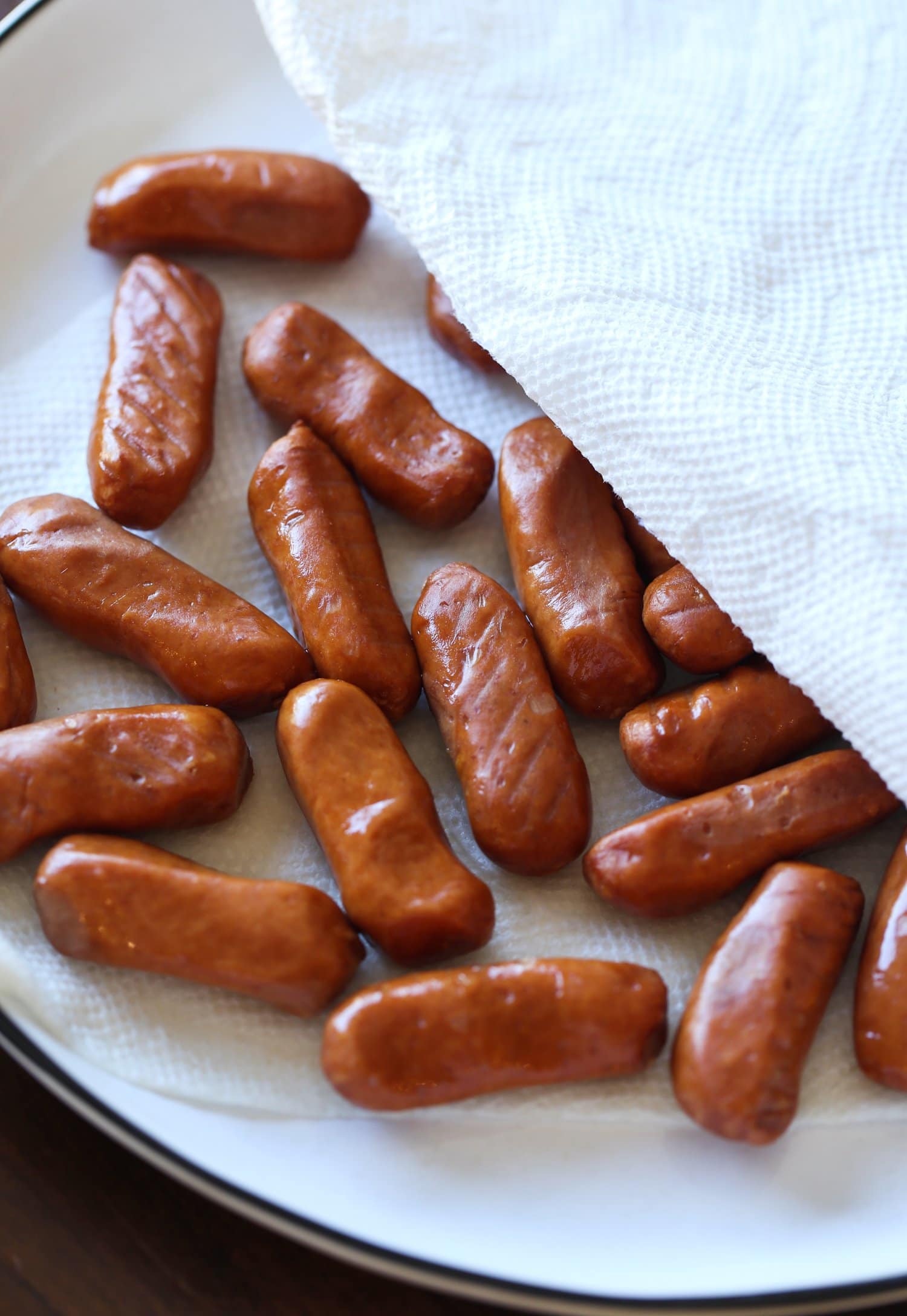 Cocktail wieners patted dry on a plate.