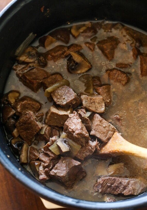 Cubes of cooked sirloin steak in beef broth with mushrooms.