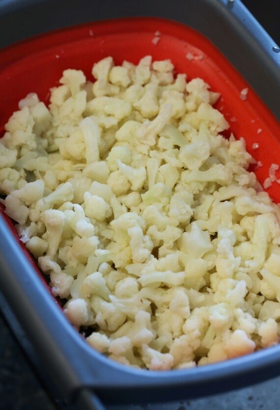 Cooked cauliflower florets in a colander, draining.