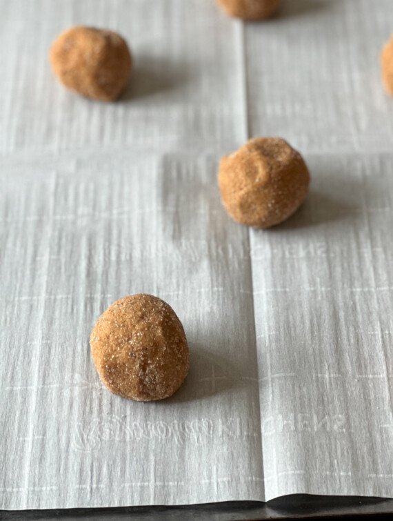 pumpkin cookie dough balls on a baking sheet with parchment paper