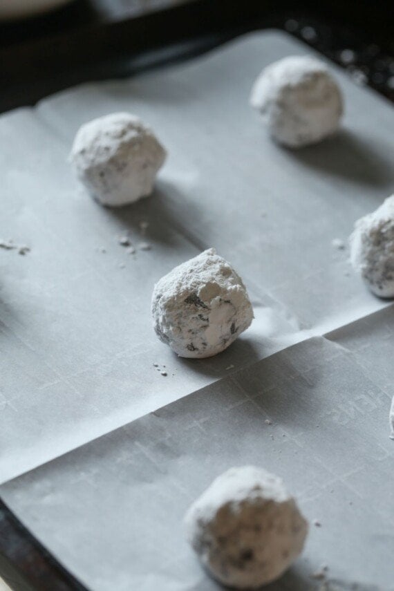 A baking sheet lined with parchment, with unbaked crinkle cookies lined up at even intervals.