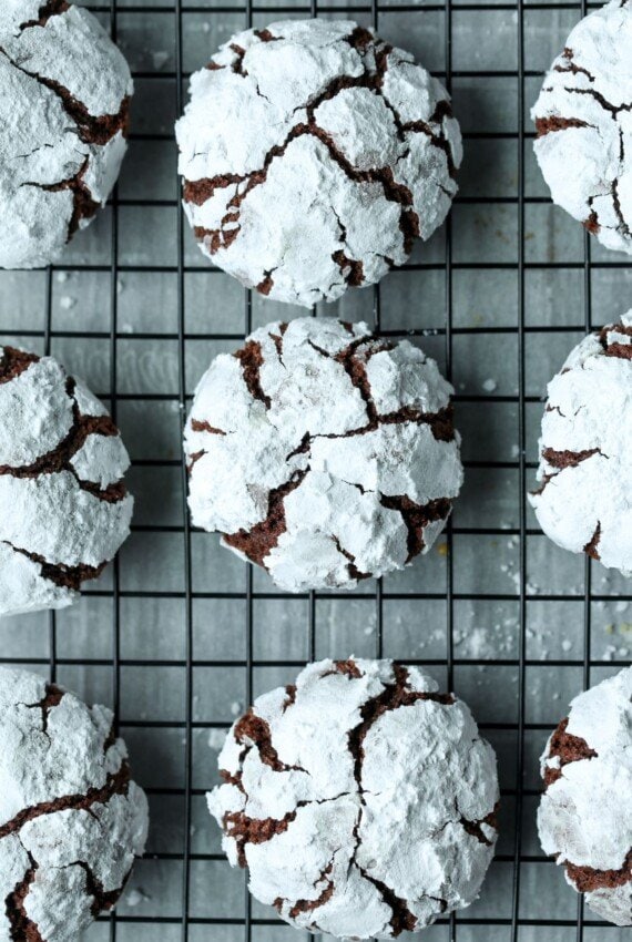 Baked crinkle cookies, cooling on a wire rack over a parchment-lined baking tray.