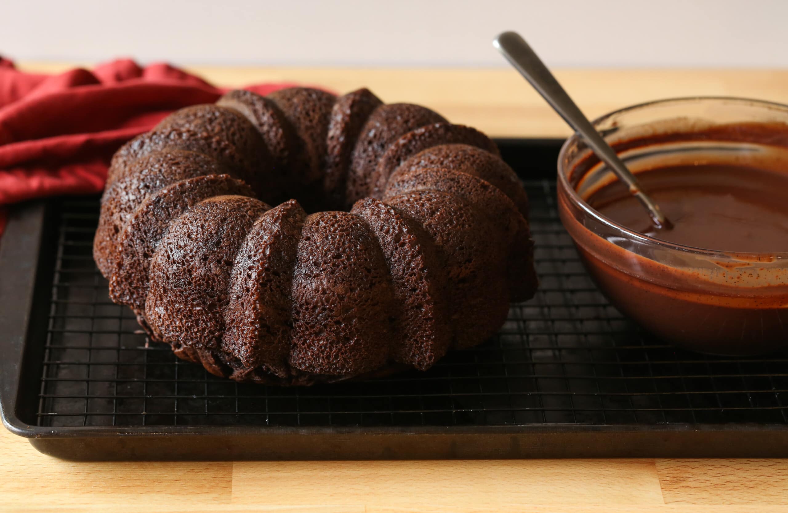 chocolate bundt cake on a cooling rack with ganache in a bowl