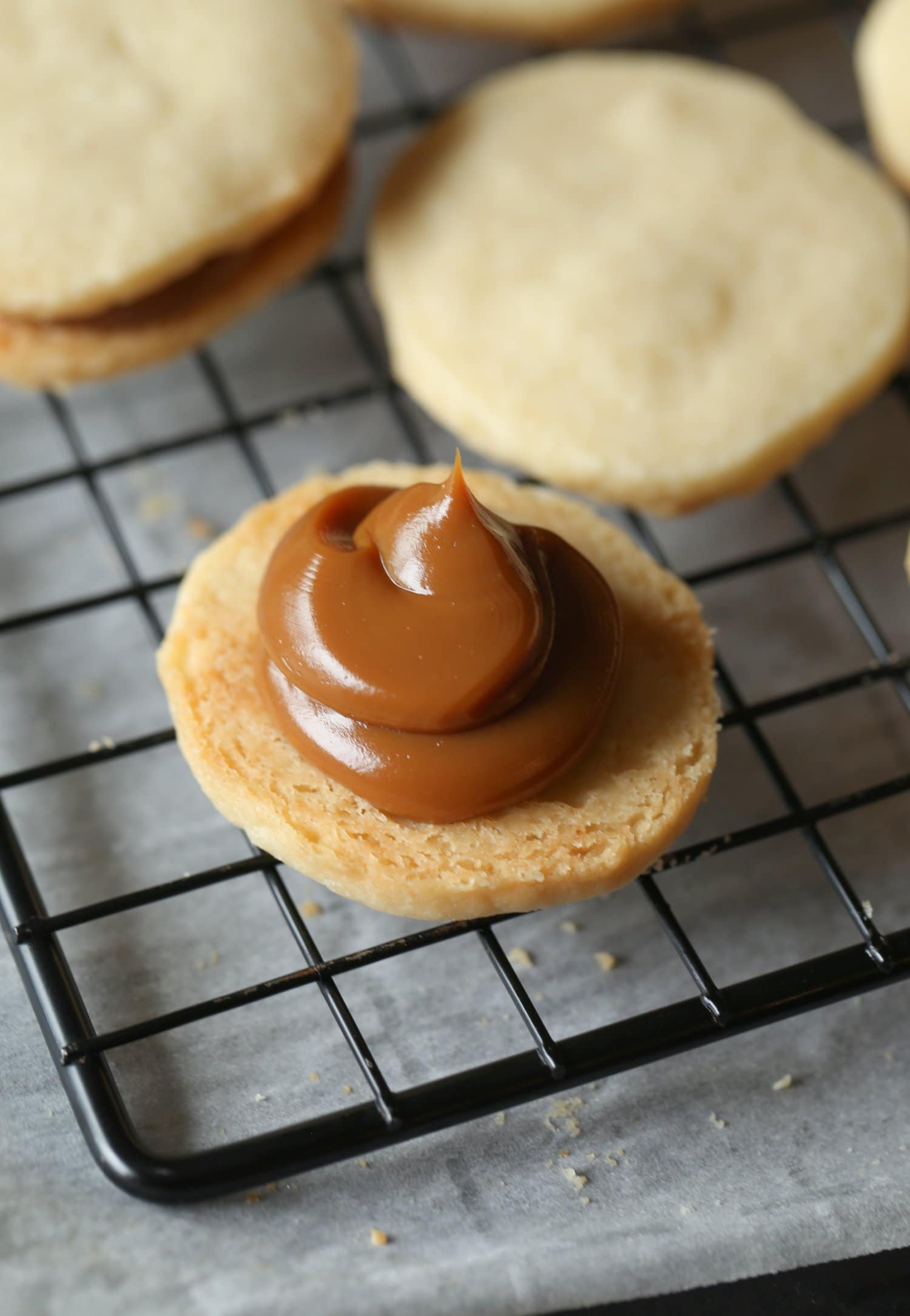 An open faced alfajor cookie with a spoonful of dulce de leche filling.