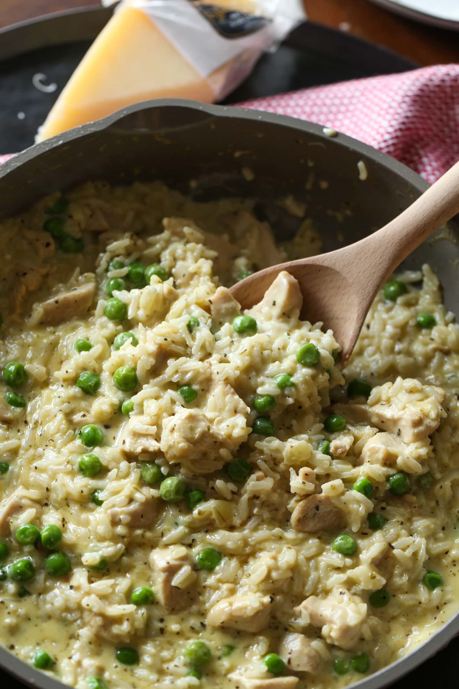 A wooden spoon is used to scoop creamy chicken and rice from a pot.