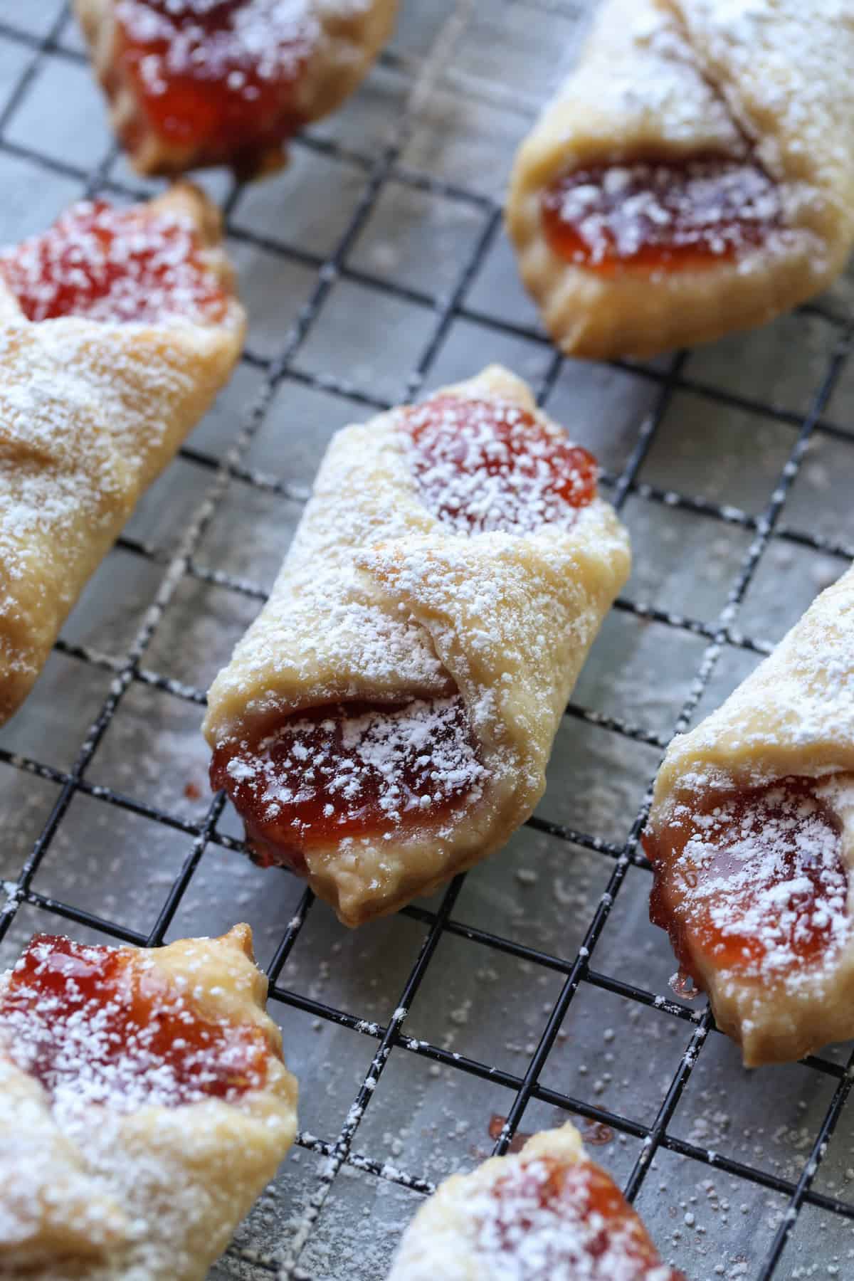 A close up of kolaczki cookies filled with strawberry preserves and dusted with powdered sugar.