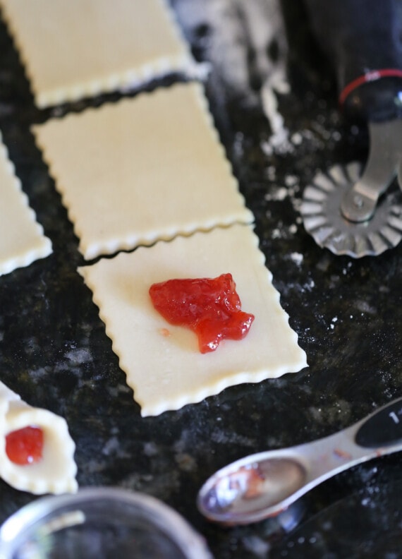 A dollop of strawberry preserve filling is placed in the center of a cookie dough square.