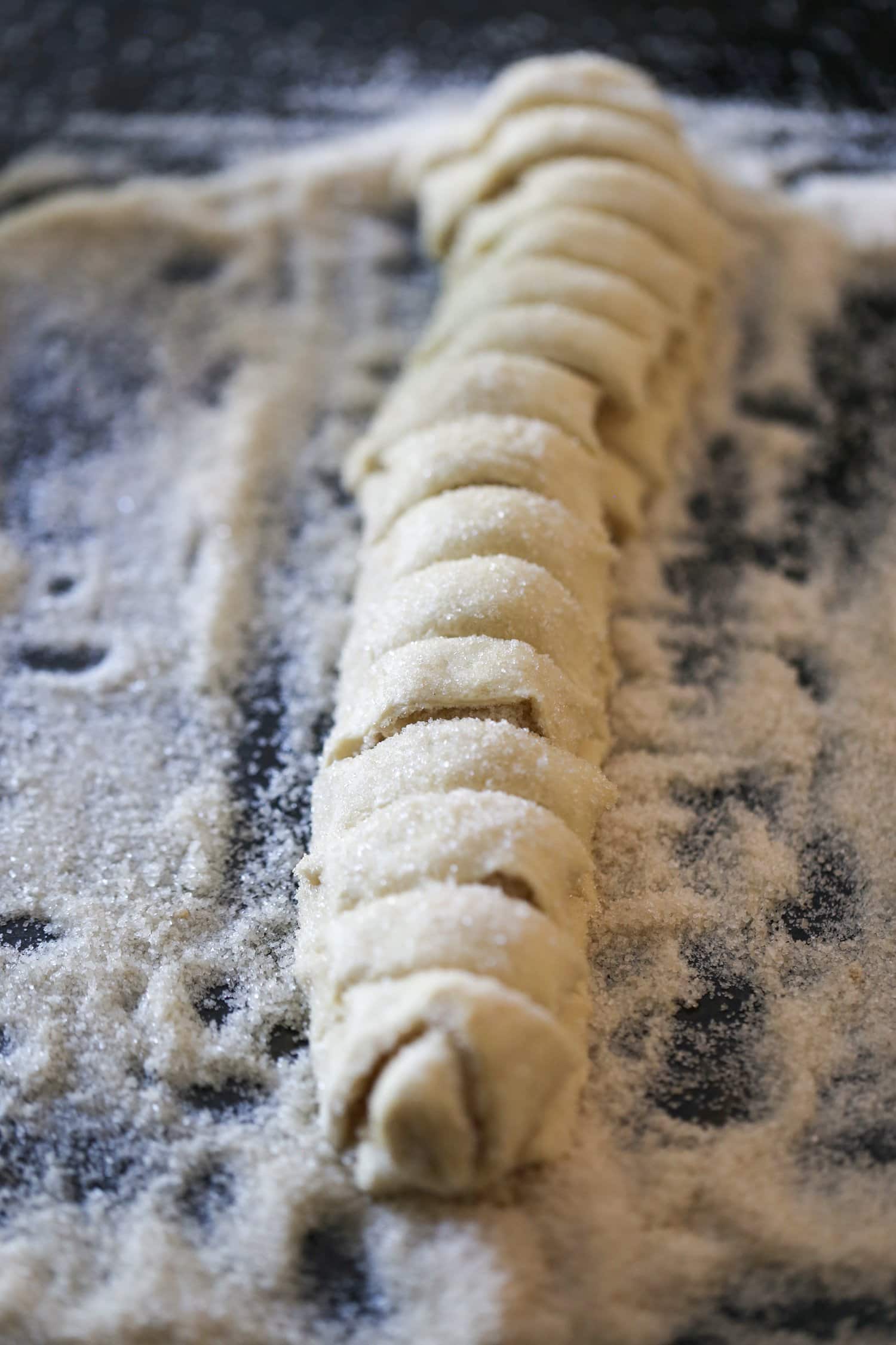 Folded and chilled palmier pastry dough is cut into half inch slices.