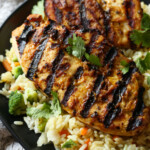 Grilled peanut butter chicken is served over a bed of rice and veggies.